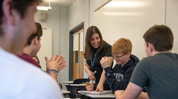 A professor working with a group of students in a classroom